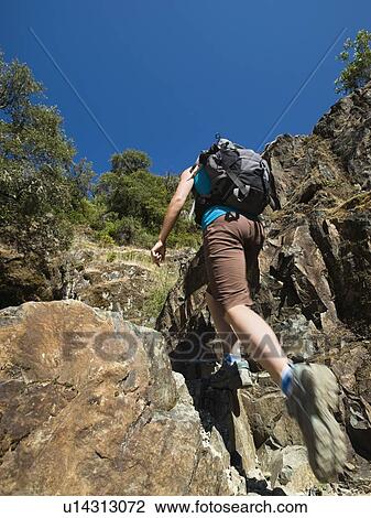 Stock Image - Hiker ascending rocky trail. Fotosearch