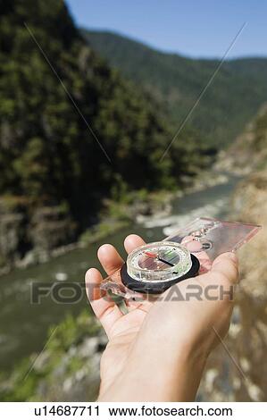 Stock Image - Hiker holding compass. Fotosearch