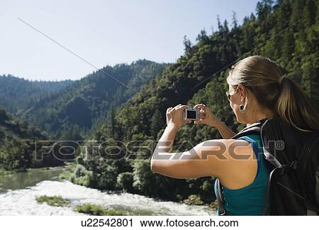 Stock Image - Hiker photographing river scene. Fotosearch