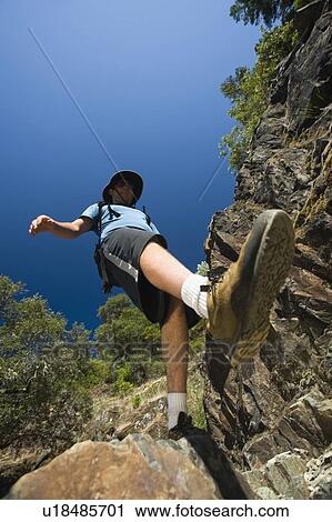 Stock Image - Hiker stepping down rocky trail. Fotosearch
