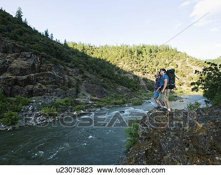 Hikers admiring view of river View Large Photo Image Stock Image - Hikers admiring view of river. Fotosearch
