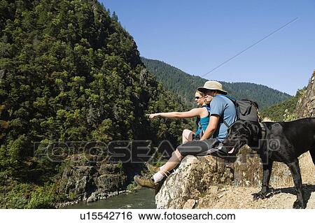 Hikers relaxing on river overlook View Large Photo Image Stock Photograph - Hikers relaxing on river overlook. Fotosearch