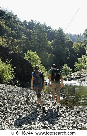 Picture - Hikers walking along river. Fotosearch