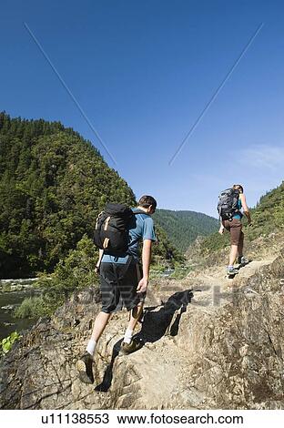 Stock Image - Hikers walking on riverside trail. Fotosearch