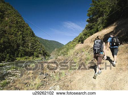 Hikers walking on riverside trail View Large Photo Image Stock Image - Hikers walking on riverside trail. Fotosearch