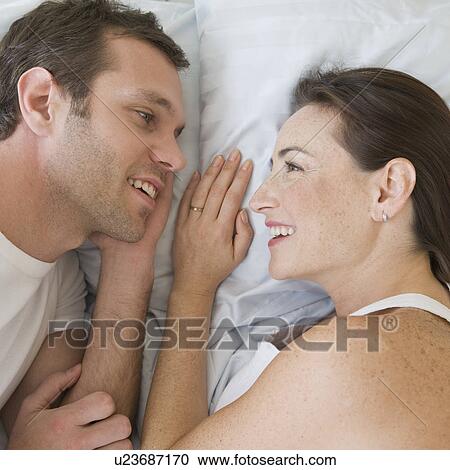 Stock Image - Hispanic couple laying in bed. Fotosearch