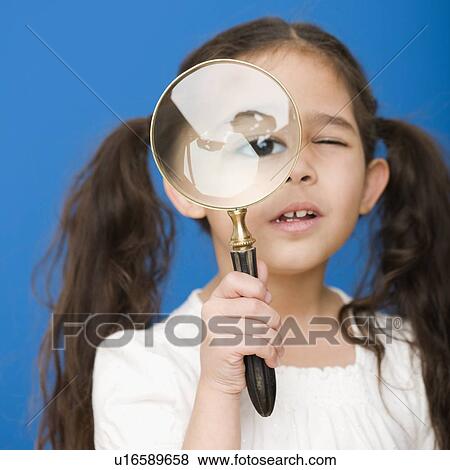 Stock Photo - Hispanic girl looking through magnifying glass. Fotosearch