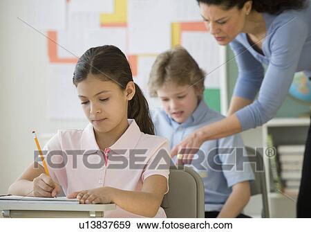 Stock Photo - Hispanic girl writing at school desk. Fotosearch