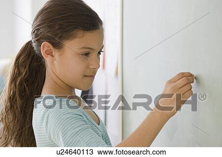 Stock Image - Hispanic girl writing on blackboard. Fotosearch
