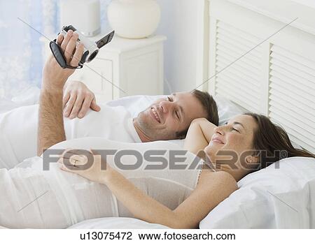 Stock Image - Hispanic man video recording pregnant wife. Fotosearch