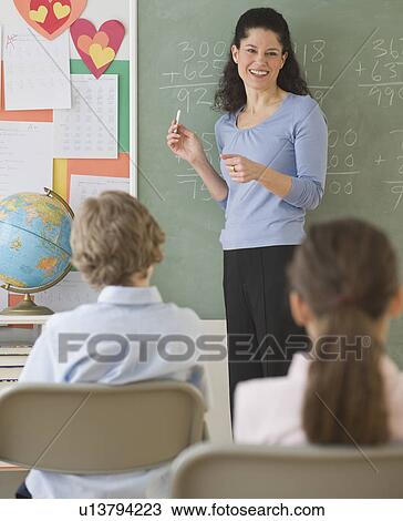Hispanic teacher in front of blackboard View Large Photo Image Stock Image - Hispanic teacher in front of blackboard. Fotosearch