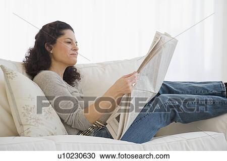 Stock Image - Hispanic woman reading newspaper. Fotosearch