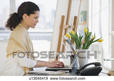Hispanic woman typing on laptop View Large Photo Image Stock Photo - Hispanic woman typing on laptop. Fotosearch