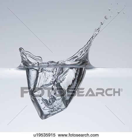 Stock Photography - Ice cube splashing in water. Fotosearch