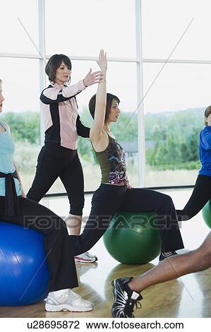 Stock Image - Instructor guiding fitness class. Fotosearch