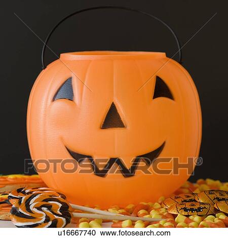 Stock Image - Jack-o-lantern pail and Halloween candy. Fotosearch