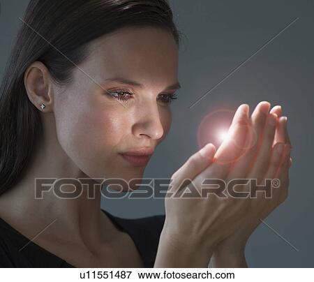 Stock Photo - Light shining from woman’s hands. Fotosearch