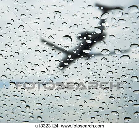 Picture - Low angle view of airplane through rain drops on window. Fotosearch