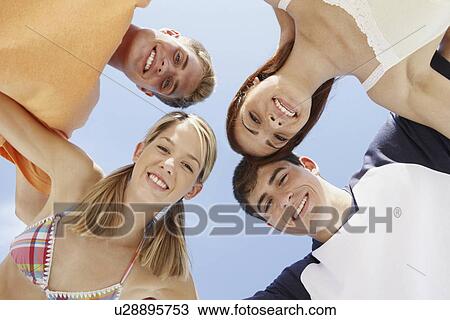 Stock Image - Low angle view of friends in a huddle. Fotosearch