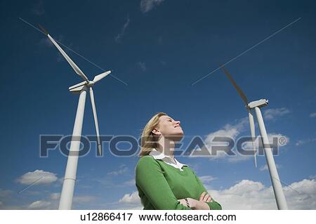 Low angle view of woman and wind turbines View Large Photo Image Stock Photo - Low angle view of woman and wind turbines. Fotosearch