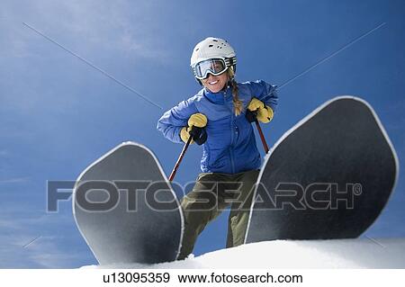 Stock Photo - Low angle view of woman on skis. Fotosearch