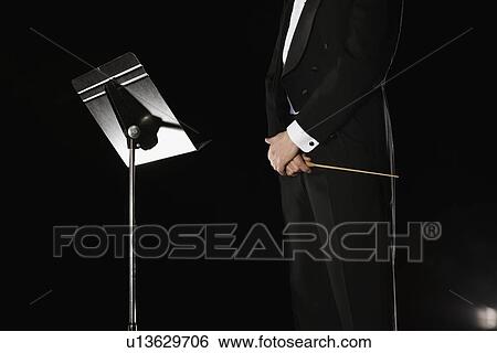 Stock Photograph - Male conductor standing next to music stand. Fotosearch
