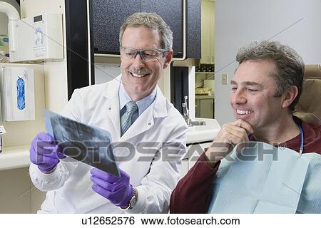 Male dentist and patient looking at x-ray View Large Photo Image Stock Photograph - Male dentist and patient looking at x-ray. Fotosearch