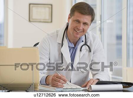 Stock Photograph - Male doctor posing at desk. Fotosearch