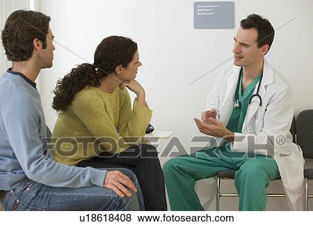 Stock Photo - Male doctor talking to couple in waiting room. Fotosearch