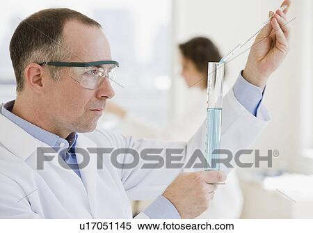 Stock Photography - Male scientist measuring liquid in vial. Fotosearch
