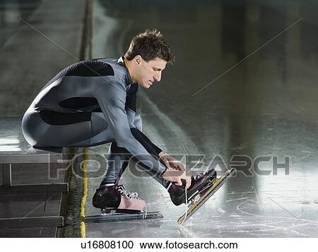 Stock Image - Male speed skater ties skate lace. Fotosearch