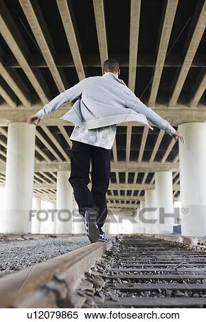 Stock Photography - Man balancing on railroad tracks. Fotosearch