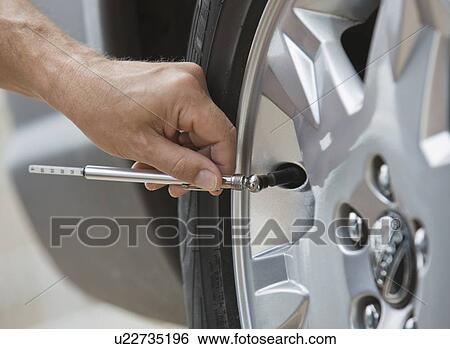 Stock Photograph - Man checking car tire pressure. Fotosearch