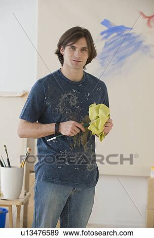 Man cleaning paintbrush in front of easel View Large Photo Image Stock Photo - Man cleaning paintbrush in front of easel. Fotosearch