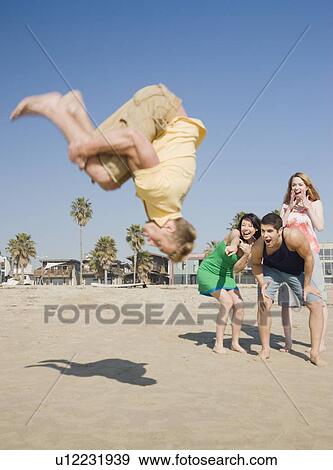 Stock Photo - Man doing back flip on beach. Fotosearch