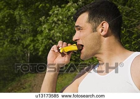 Man eating energy bar View Large Photo Image Stock Photography - Man eating energy bar. Fotosearch