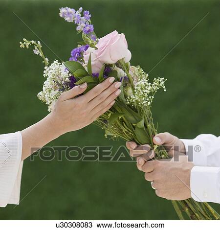 Man giving woman bouquet of flowers View Large Photo Image Stock Image - Man giving woman bouquet of flowers. Fotosearch