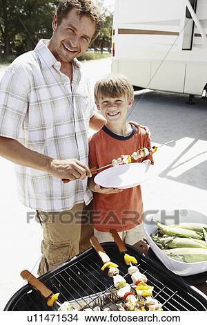 Picture - Man grilling dinner for family on beach. Fotosearch