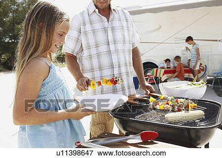 Man grilling dinner for family on beach View Large Photo Image Stock Photo - Man grilling dinner for family on beach. Fotosearch