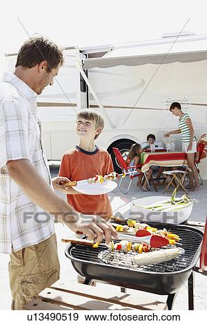 Man grilling dinner for family on beach View Large Photo Image Stock Photo - Man grilling dinner for family on beach. Fotosearch