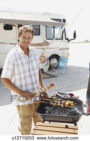 Man grilling shish kebabs on beach View Large Photo Image Stock Image - Man grilling shish kebabs on beach. Fotosearch