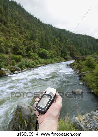 Man holding gps unit by river View Large Photo Image Picture - Man holding gps unit by river. Fotosearch