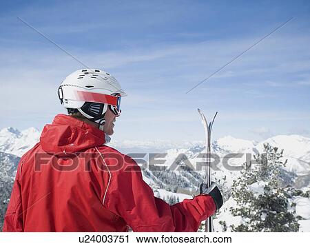 Stock Image - Man holding skis. Fotosearch