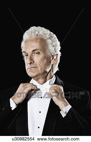 Man in tuxedo adjusting bow tie View Large Photo Image Picture - Man in tuxedo adjusting bow tie. Fotosearch