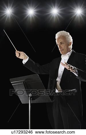 Man in tuxedo conducting under lights View Large Photo Image Stock Photograph - Man in tuxedo conducting under lights. Fotosearch