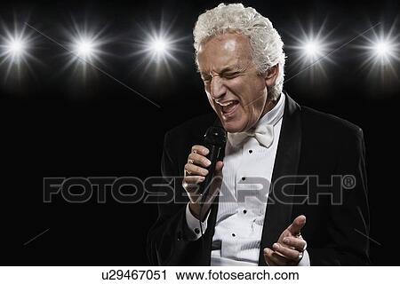 Stock Image - Man in tuxedo singing into microphone. Fotosearch