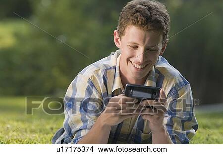 Man laying in grass and text messaging View Large Photo Image Picture - Man laying in grass and text messaging. Fotosearch