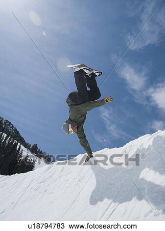 Stock Image - Man performing trick on snowboard. Fotosearch
