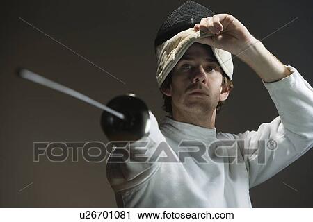 Stock Image - Man pointing fencing foil and lifting mask. Fotosearch