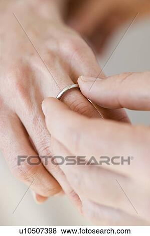 Stock Photo - Man putting wedding ring on woman’s finger. Fotosearch